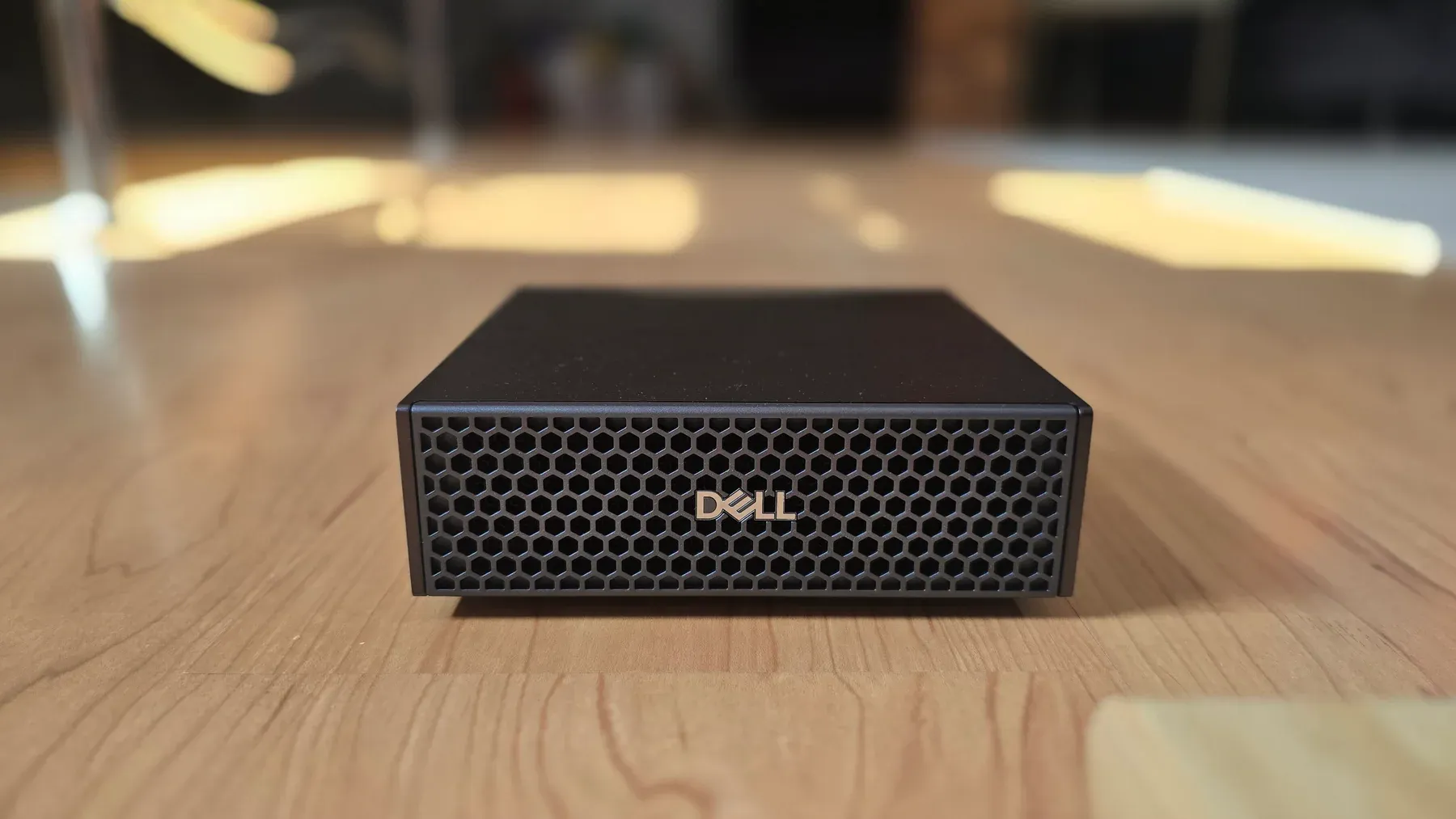 Front of the Dell Pro Max with GB10 on a wooden desk, showing the honeycomb grille and Dell logo